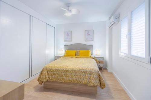 马拉加Nosquera FreshApartaments by Bossh! Apartaments的白色卧室配有黄色枕头的床