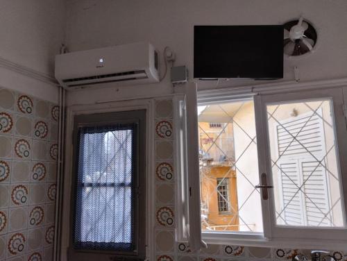 比雷埃夫斯Ήσυχο σπίτι στο Μικρολίμανο的一间设有镜子和窗户上方电视的客房
