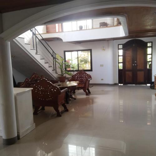 TumauiniMadria's Pension House Reddoorz的客厅配有椅子和桌子,设有楼梯