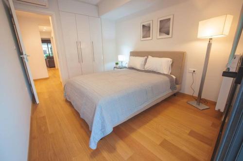 雅典Voula Luxury Apartment的一间卧室配有一张床和一盏灯,铺有木地板