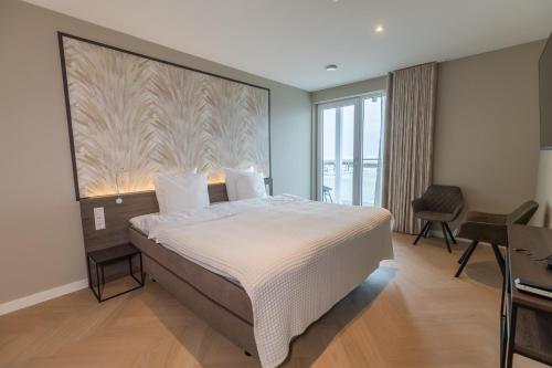 卡德赞德-班得Residentie de Schelde - Apartments with hotel service and wellness的一间卧室配有一张大床、一张桌子和一个窗户。