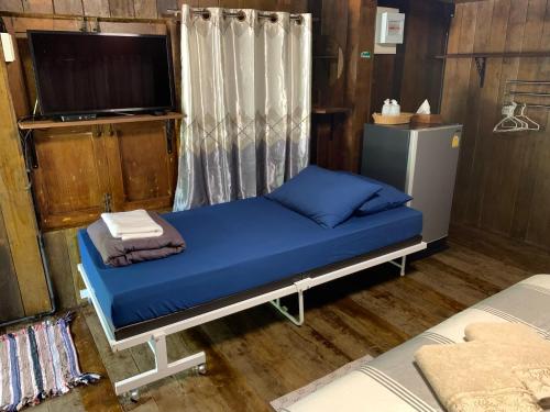 Ban Khlong Khenเมี่ยงไม้ รีสอร์ท的一间卧室配有一张带蓝色床单的床和一台电视。