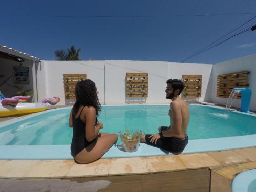 马拉戈日Barra Grande Pousada的坐在游泳池里的男人和女人