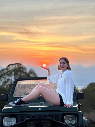 库布盼洛坎Batur volcano sunrise jeep的坐在卡车后面的女人,欣赏日落