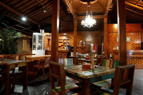 DalungNorth Wing Canggu Resort的餐厅设有木桌、椅子和吊灯。