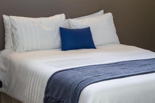 姆巴巴内Waterford Executive Apartments的一张白色的床,上面有蓝色的枕头