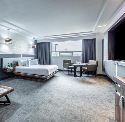 托卢卡Suites Inn la Muralla Hotel & Spa的一间酒店客房,配有一张床铺、一张桌子和一台电视
