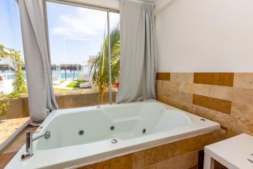 曼克拉Hotel Del Mar Mancora的带浴缸的浴室和大窗户