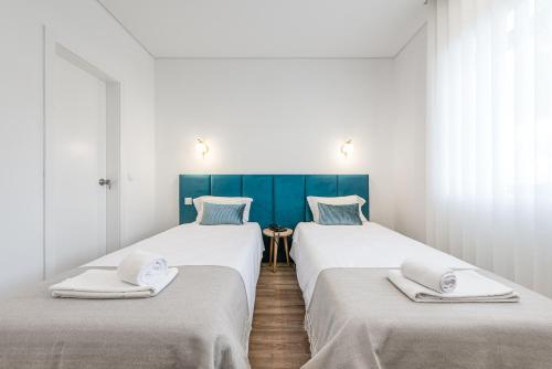 波尔图里约大酒店的白色和蓝色的客房内的两张床