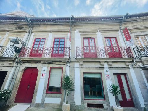 维亚纳堡Rua Grande Hotel的一座有红色门窗和棕榈树的建筑