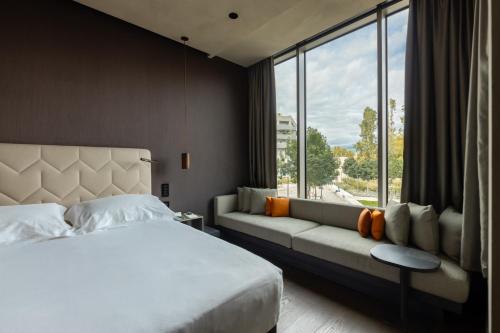 米兰Hotel VIU Milan, a Member of Design Hotels的一间卧室配有一张床、一张沙发和一个窗口