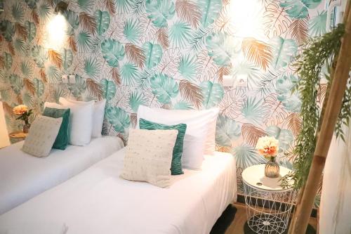圣加蒂安代布瓦Maria Grazia Hotel的客房配有两张带枕头和壁纸的床。