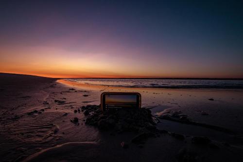 托普赛尔海滩Sea Vista Motel的日落时坐在海滩上的椅子
