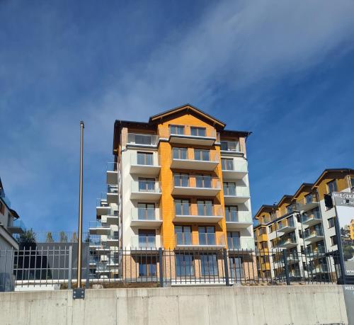 卡尔帕奇Apartamenty z widokiem na Śnieżkę的围栏前高高的公寓楼