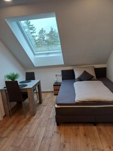 吉贝尔施塔特Bianca's Ferienwohnungen的一间卧室配有一张床、一张桌子和一个天窗