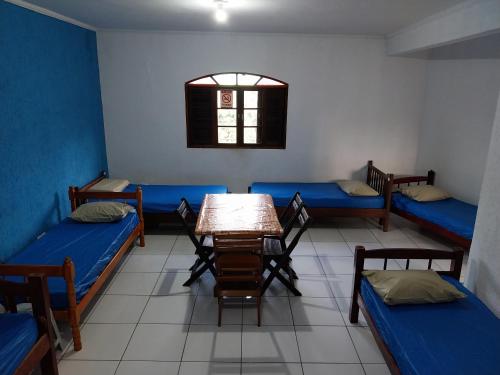 平达莫尼扬加巴POUSADA PERLLA's Pindamonhangaba的带三张床和桌椅的房间