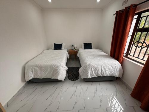 利文斯顿White Rhino apartments & tours的带窗户的客房内设有两张单人床。