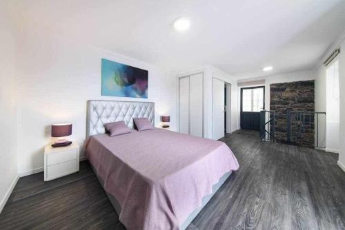 卡列塔Lombo do Doutor Cottage 2的一间卧室配有一张大床和紫色毯子