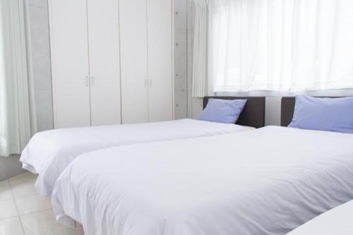 ShirahoShiraho Villa - Vacation STAY 20487v的卧室内的两张床,配有白色的床单和蓝色的枕头