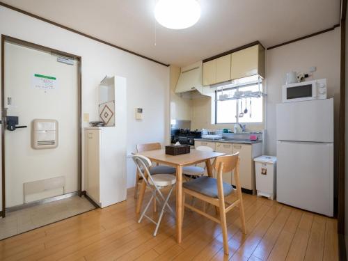 东京maison elegance - Vacation STAY 15799的厨房配有桌椅和冰箱。