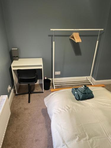 波特斯巴Single Room in Potters Bar Hertfordshire的一间卧室配有一张床、一张桌子和一把椅子