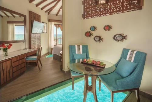 普拉亚卡门Palafitos Overwater Bungalows Catamarán, Cenote & More Inclusive的客厅和带桌椅的用餐室