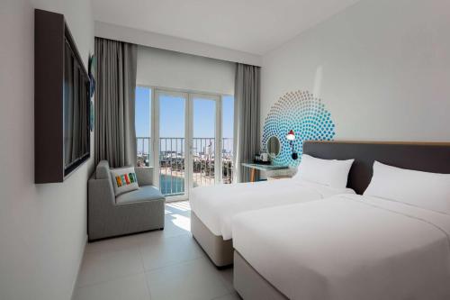 迪拜Rove La Mer Beach, Jumeirah的酒店客房设有两张床和一个阳台。