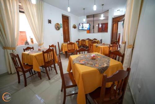 卡哈马卡El Cumbe Inn的用餐室配有黄色桌椅和电视