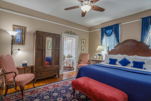 圣奥古斯丁Victorian House Bed and Breakfast的一间卧室配有一张床和椅子以及吊扇