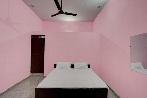 诺伊达OYO Hotel star palace的粉红色的客房设有一张床和一个吊扇