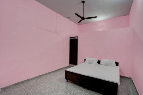 诺伊达OYO Hotel star palace的粉红色的客房设有一张床和一个吊扇