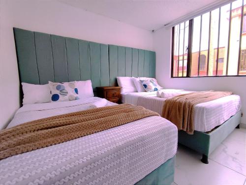 派帕Casa Cielo en Paipa Centro的一间卧室设有两张床和两个窗户。