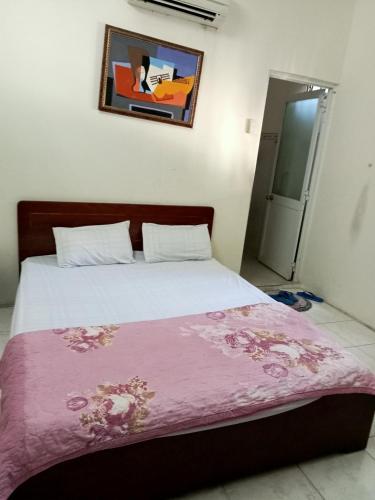 头顿Nhà nghỉ MINH HOÀNG的一间卧室配有一张床铺,床上铺有粉色毯子
