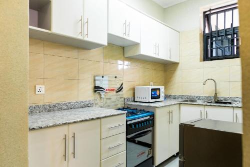 基加利The Vacation Homes Apartments的厨房配有白色橱柜和炉灶烤箱。