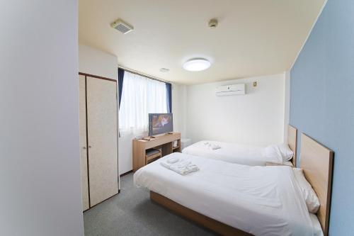 大阪ホテルよしや的一间卧室设有两张床和窗户。
