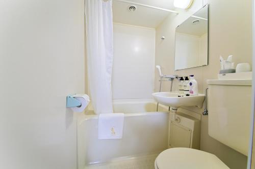 大阪ホテルよしや的白色的浴室设有水槽和卫生间。