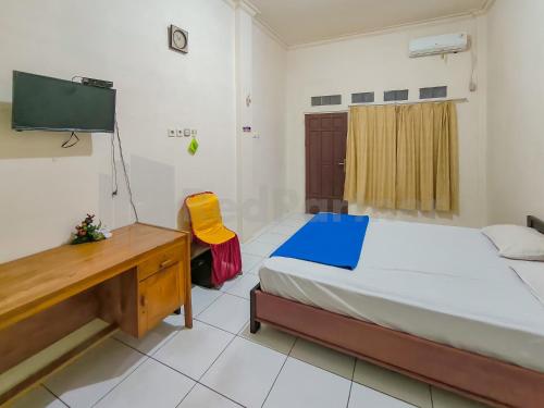 TumbangrunganGriya Tambun Raya RedPartner的一间卧室配有一张床、一张书桌和一台电视