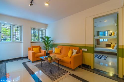 班加罗尔Zostel Bangalore (Koramangala)的客厅配有2张橙色沙发和1张桌子