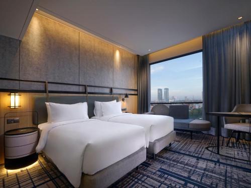 泗水Mercure Surabaya Manyar的酒店客房设有两张床和大窗户。