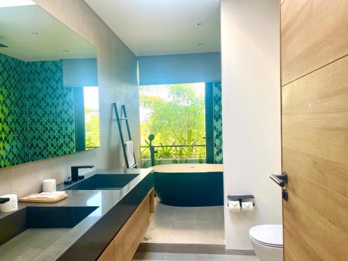 富国Moon Villa Phu Quoc - 3 Bedroom - Private pool的浴室配有蓝色水槽和浴缸。