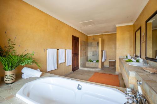 维兰库卢什Collection Luxury Accommodation: Quinta Do Sol, Vilanculos, Mozambique的大型浴室设有两个盥洗盆和浴缸。