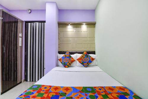 kolkataFabExpress Laxmi Inn的一间卧室配有一张带色彩缤纷枕头的大床