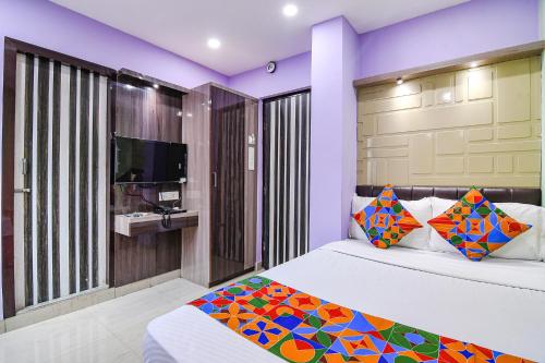 kolkataFabExpress Laxmi Inn的一间卧室配有一张带色彩缤纷枕头的床和一台电视。