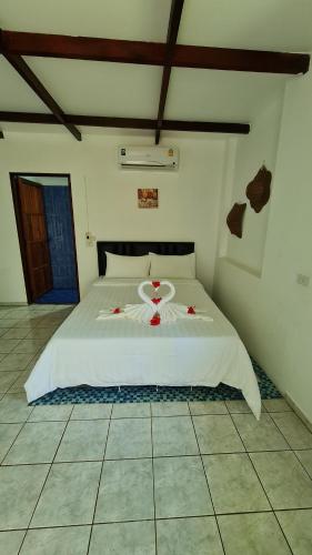 麦岛Koh Mak Garden View的卧室配有白色的床铺,上面有红色的鲜花