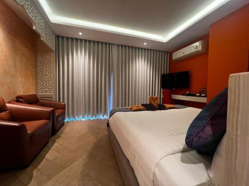 芭东海滩Le Maroc Hotel Patong的一间卧室配有一张床、一张沙发和一把椅子