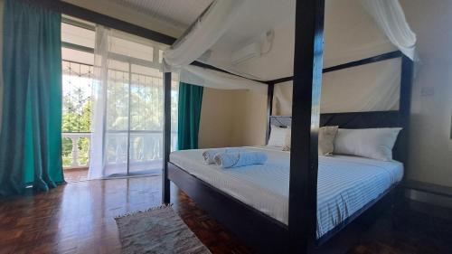 蒙巴萨Ary Homestay Nyali - On Corral Drive的一间卧室设有一张天蓬床和大窗户