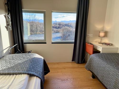 JarðlangsstaðirBakki的一间卧室配有两张床、一张桌子和两个窗户。