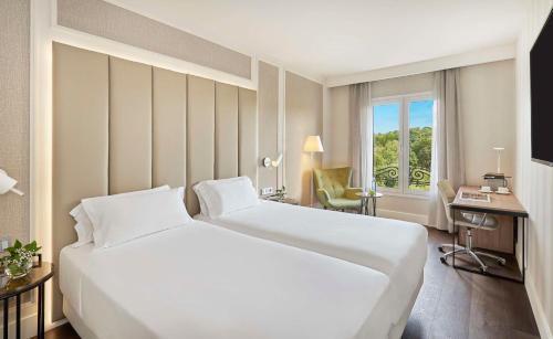 马德里NH马德里纳克纳尔酒店的酒店客房设有一张白色大床和一张书桌