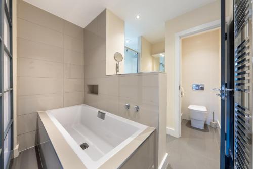 特威克纳姆Candler Mews - Twickenham的一间带大型白色浴缸和卫生间的浴室
