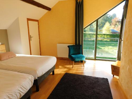 NébouzatGites et Cocon des Puys的一间卧室设有两张床、一张蓝色椅子和窗户。